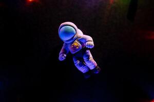 The figure of an astronaut made of polymer clay on a black background. Minimalistic shot of toys. Glare from the garland photo