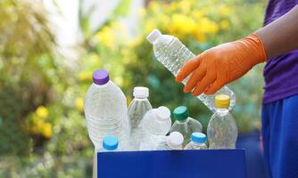 Hand holds used plastic bottle to put in junk bin for recycling. Concept, sorting garbage campaign before throw away for reuse or recycle. Environment conservation. Eco friendly activity. photo