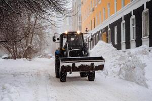 A tractor cleans snow in the city. Clearing the street of snow after a snowstorm. Ufa Russia. Clean streets. Winter in the city. photo