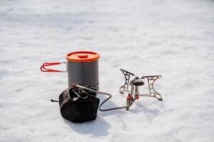 Gas tourist burner for cooking on a hike, equipment for hiking, a set of dishes made of metal, a light pot with a lid, snow winter cold photo