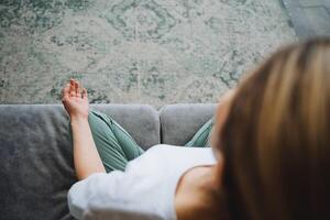 A view from above of a girl in the lotus position, meditating sitting on the couch in her house. The concept of Zen practice in the apartment. The hand of chin mudra. photo