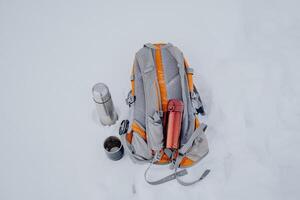 Top view of the tourist backpack. several thermoses lie on the snow. photo