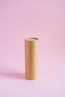 Craft tube for storing pencils and pens. The tuba stands on a pink background. Eco-friendly cardboard boxes photo