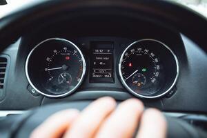 A close shot of the dashboard of the car. Speedometer and tachometer indicator. Driving an expensive car. On the steering wheel lies the driver's hand photo