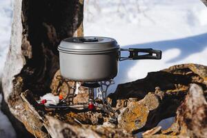 Tourist utensils, a pan stands on a burner, cooking on a camp burner, cooking in camping conditions in winter. photo