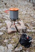 The pot stands on a gas burner against the background of stones, cooking on a hike, camping in nature, camping on a hiking adventure in the mountains. photo