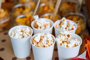 Cups of popcorn with caramel. Crispy sweetness. A bucket of popcorn for a trip to the movies. Five servings of delicious popcorn with caramel photo