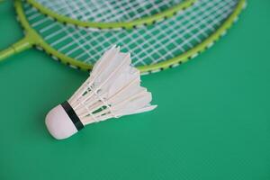 Shuttlecock and rackets. Badminton sport equipments on green background. Concept, sport, exercise, recreation activity for good health. Popular sport for all genders photo