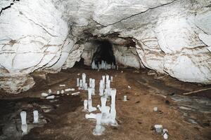 Icicles ice on the floor of a karst cave, a hike in winter in the cold underground cave, ice stalagmites, a speleological expedition. photo