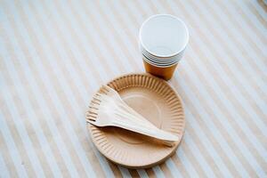 A set of paper dishes. Eco materials for cutlery. Glasses, forks, plates. Recyclable raw materials. photo