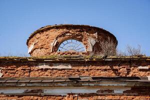 un fragmento de un antiguo rojo ladrillo edificio, un antiguo de forma redonda estructura, un arqueado ventana en el torre de el antiguo templo. foto