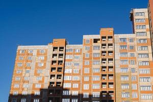 The house is being built against the background of a blue sky. Residential complex of red brick, layout of apartments in the house. Luxury housing. photo