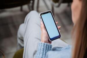 The hand holds the phone. A mobile cellular device lies in a woman's hand. Blank screen. A modern gadget to call a friend. photo