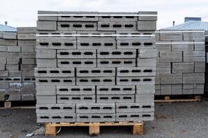 The packaging of concrete blocks lies on a pallet, the packaging of bricks is stacked in a heap, holes in the bricks, building material, a construction site, a storage warehouse. photo