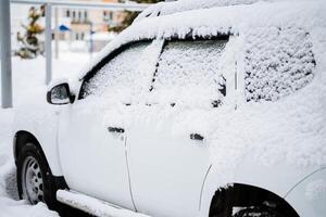 el coche es cubierto con nieve. nevada en el ciudad. equipo debajo el ventisquero. el coche tiene atascado en el nieve en el invierno. sin limpiar calles de el metrópoli. foto