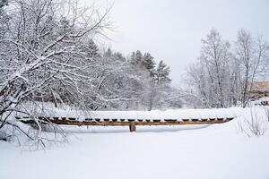 A magnificent winter landscape with a small wooden bridge across the river. Frozen water surface. Winter walks by the riverbank photo