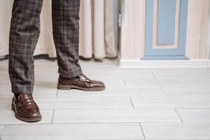 A classic pair of shoes on men's feet. Shoes are on the floor. Plaid trousers, brown shoes. Clothes for guys casual style photo