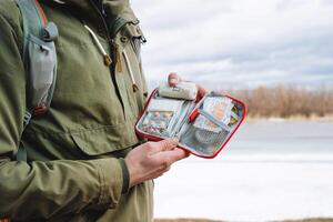 A bag with medicines, a first-aid kit in the hands of a tourist, tablets in a package, a patch for a wound, a band-aid, emergency medical care in the forest, health protection. photo