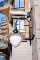 Street lighting lamppost is attached to the wall of the building. Outdoor street lighting. Cityscape. photo