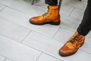 elegante botas en brillante naranja. un par de Zapatos son desgastado en su pies. de los hombres casual estilo zapatos, vistoso retro zapatos, genuino cuero, hecho a mano. foto