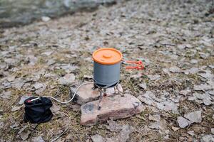 Tourist gas burner on top is a pot of food, dishes for a hike, cooking in the forest. Tourist equipment, equipment. photo