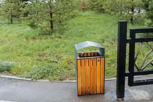A wooden garbage can, an empty container for garbage collection on the street, a city park sidewalk waste bin. photo