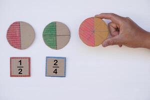 matemáticas enseñando materiales acerca de fracción. mano sostiene circulo papel a espectáculo partes de color separación. concepto, educación. bricolaje arte como enseñando ayuda en matemáticas sujeto. foto