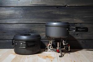 A set of camping utensils. Portable burner and dark stainless steel pans. Camping, eating outdoors. Gas burner photo