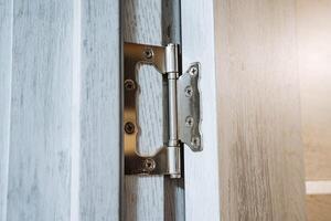 A close shot of a metal hinge for a wooden door. Interior door with hinges. Mandatory fittings in repair. Modern house and interior in it photo
