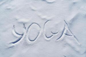 The word yoga is written in the snow. The letters of the meditation of the Vedic culture on a white background. The concept of Zen is a symbol of calm and quiet. photo