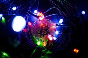 Bitcoin coin lies among the New Year's garlands. Souvenir coin. Digital money in the modern world. The growing market of electronic money photo