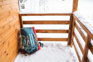 A bright hiking backpack lies on the snow. A climbing rope is tied to a backpack. In the side pocket of the thermos. Hiking in winter. Rocks and forests photo