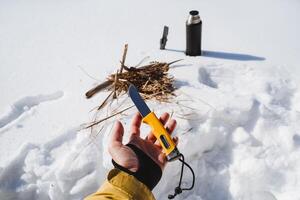 un mano sostiene un agudo cuchillo, un espada descansa en el palma de tu mano, equipo para supervivencia en el salvaje condiciones de un frío invierno, un bushcraft en naturaleza. foto