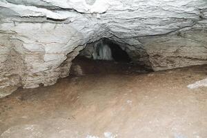 subterráneo cueva profundo, largo paso en el karst cavidad de el montaña, oscuridad a el final de el túnel, espeleología, foto