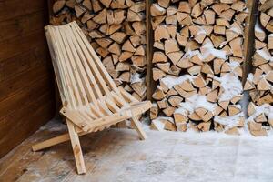 jardín coche postal longue hecho de madera. jardín silla para al aire libre asientos, registros Cortado abedul leña en un registro. apilado leña en el patio interior. foto