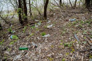 Garbage is an environmental disaster pollution, plastic bottles lie in the forest poisoning the earth, human waste on the river bank. photo