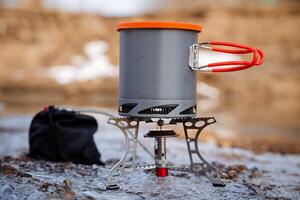 The pot stands on a gas burner against the background of the forest, the dishes hike are shot close-up, a pan with a radiator for heat, an energy condenser, an ultra light bowler gear photo