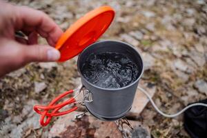 A pot of boiling water stands on a gas burner shot close-up, Open the lid of the pan, Boil water on fire, tourist utensils, cooking. photo