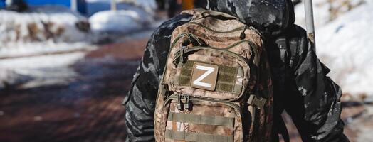 el letra z Oeste, un parche en el mochila de un militar soldado. el ruso Ejército es equipado con camuflaje, un ver desde detrás un patrullero. foto