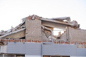 A broken house after an excavator strike, the wreckage of a building against the sky, an earthquake in the city. photo