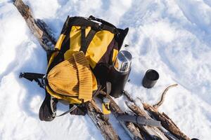 Camping equipment view from above. Equipment for a winter hike for one day. Yellow color of the backpack, hat, thermos with mug. photo