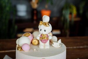 A white chocolate hare decorates a children's birthday cake, a delicious bright cake, a composition of cakes, glaze covers the cake. photo