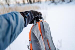 The hand holds the strap of the backpack. The tourist took a bag in his hand. photo