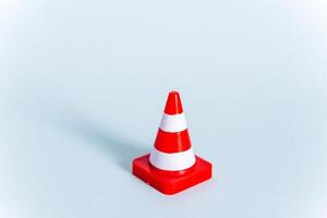 A toy road cone on a minimalist blue background. Road signs in mini-format. Rules of the road. Red signal cone photo