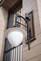 Close-up lighting. A lantern hangs outside on the wall of the house. White glass ball lamp. photo