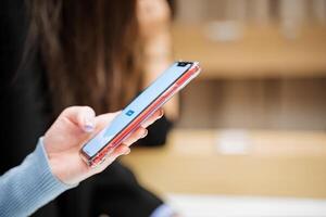 A phone in a woman's hand. Send a message on your smartphone. The screen of the mobile phone is turned on. Press your finger on the sensor. Read the text in the gadget. photo