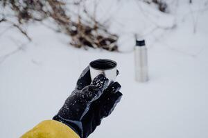 Pour the tea from the thermos into a glass. The concept of a thermal mugs with a hot drink. photo