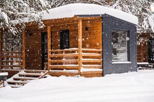 Modular house made of dark metal and light wood in winter forest. a house that takes into account everything you need for a comfortable life outside the city. photo