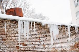 hielo carámbanos colgar en el techo, el peligro de hielo que cae en el cabeza. un sitio de aumentado peligro a vida. el amenaza de nieve que cae desde el techo. foto