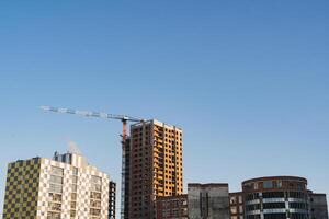 edificio un casa, un ladrillo casa en contra el cielo. grua es involucrado en el instalación trabajo de el construcción de el edificio foto